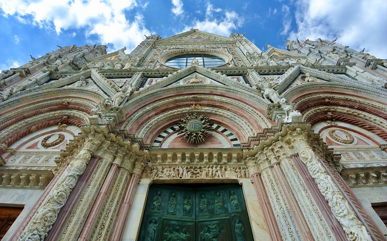 Facade of Siena Cathedral with intricate carvings and sculptures, part of city walking tour.