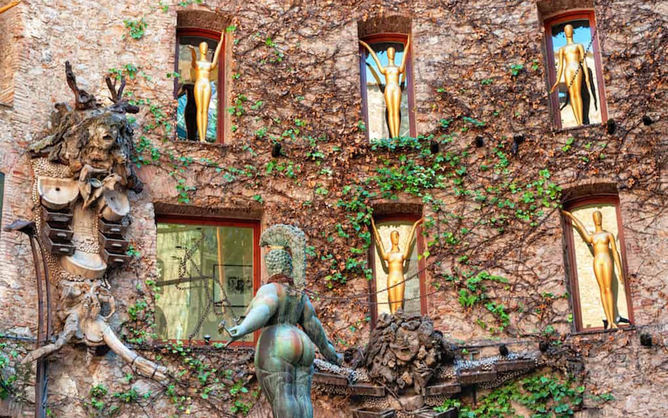 Facade of Salvador Dalí Museum in Figueres with sculptures and ivy-covered walls.