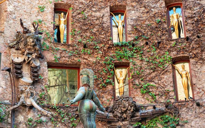 Facade of Salvador Dalí Museum in Figueres with sculptures and ivy-covered walls.