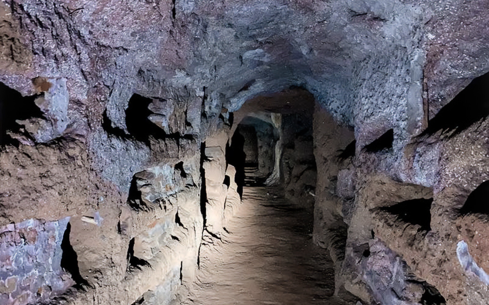 Underground passageway in Roman Catacombs, dimly lit with stone walls.