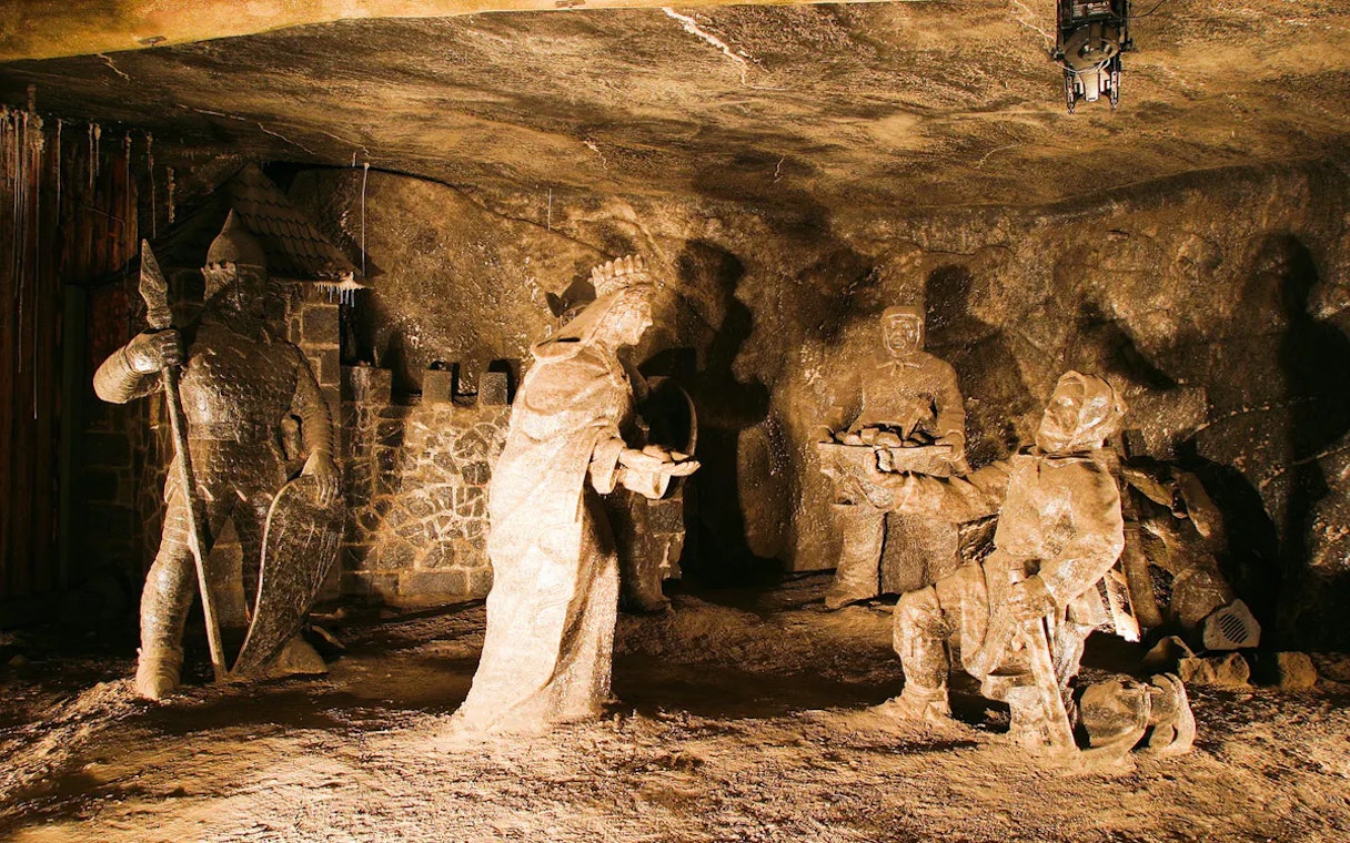 Salt sculptures in the Wieliczka Salt Mine, Poland, depicting historical figures in a dimly lit chamber.