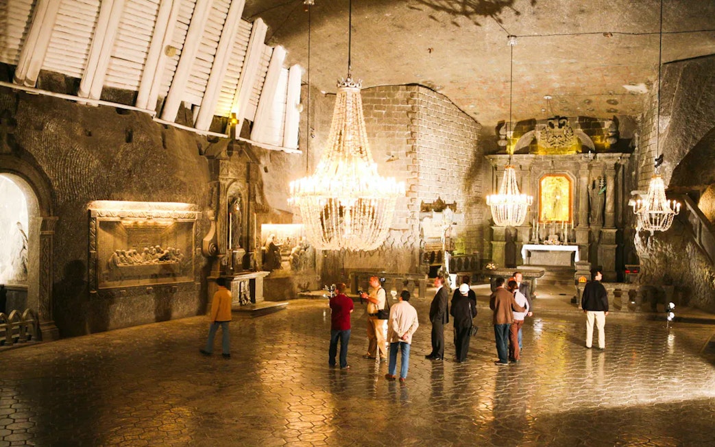 Tourists exploring the Wieliczka Salt Mine chapel with chandeliers, Poland.