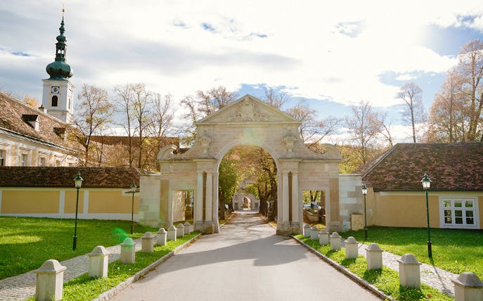 Entrance archway at Mayerling, Vienna Woods, with historic buildings and trees in the background.
