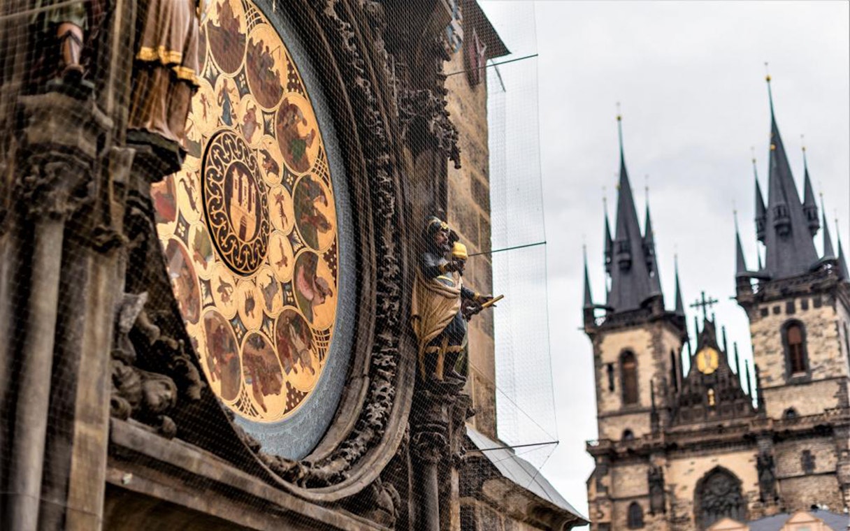 Astronomical Clock in Prague with Gothic church spires in the background.