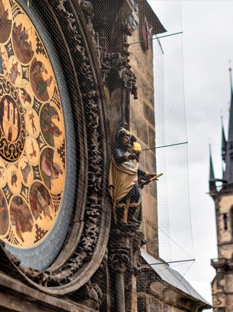 Astronomical Clock in Prague with Gothic church spires in the background.