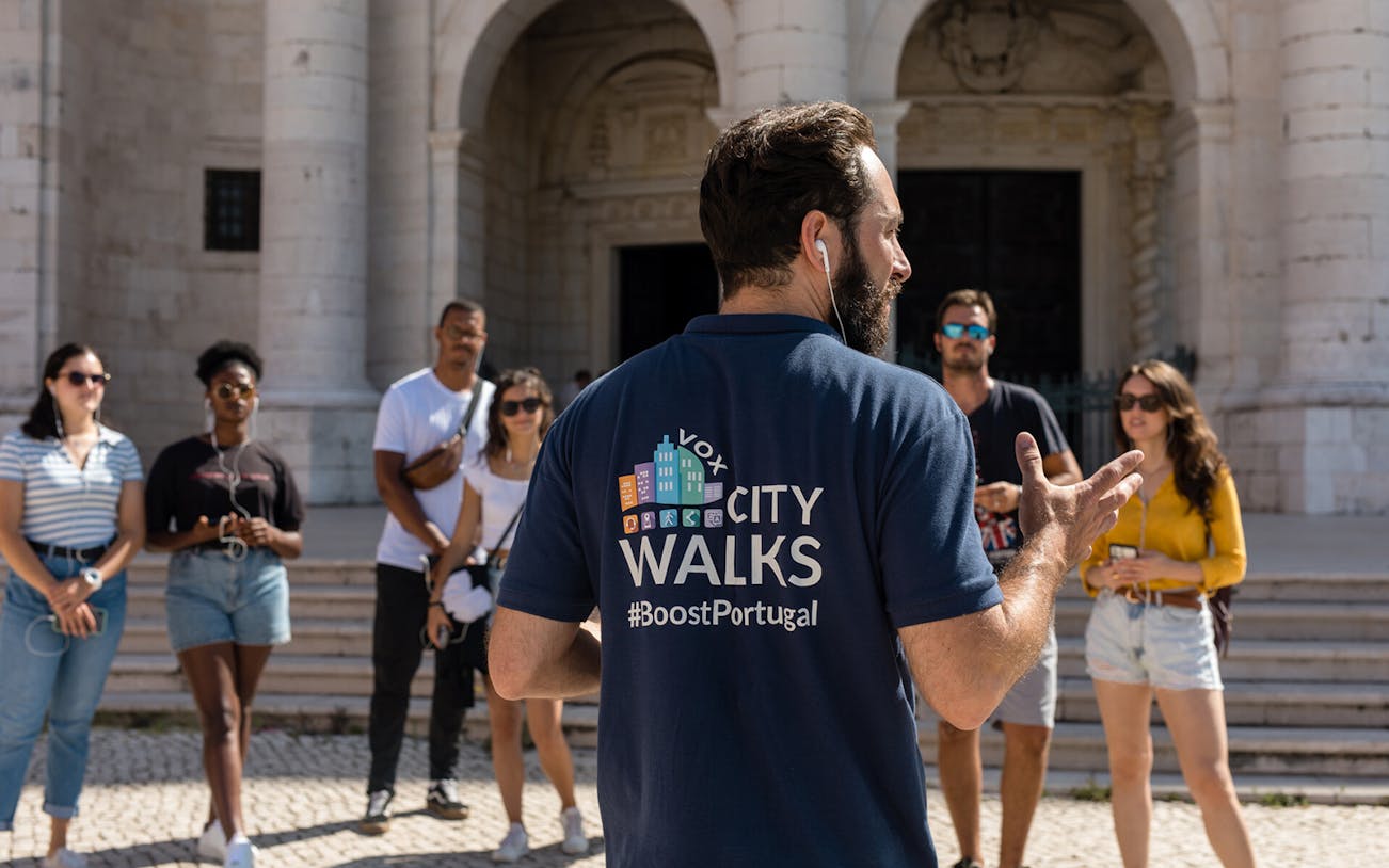 Tour guide leading a group in Lisbon, Portugal, near historical architecture.