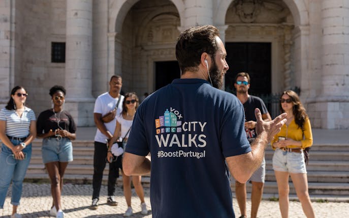 Tour guide leading a group in Lisbon, Portugal, near historical architecture.