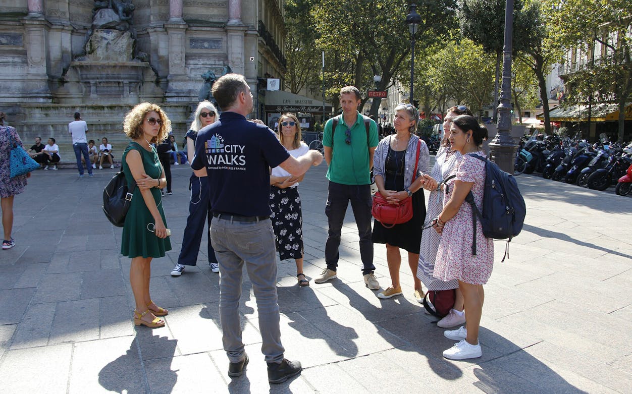Tour group listening to a guide near Saint-Michel Fountain, Paris.