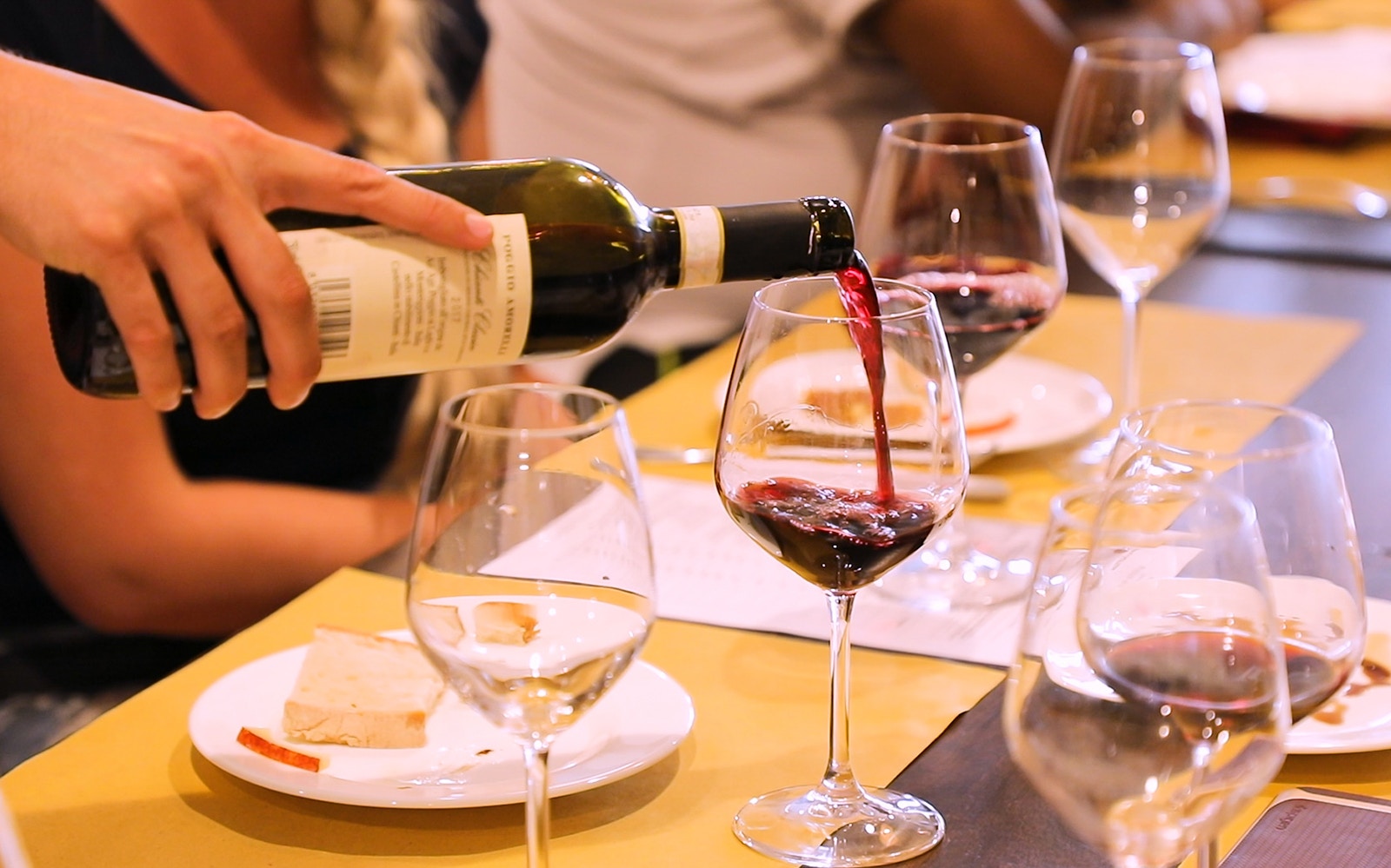 Pouring red wine into a glass during a wine tasting in Chianti, Italy.