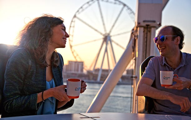 Couple enjoying coffee on Dubai Ferris wheel at sunset with Dubai Unlimited Attractions Pass.