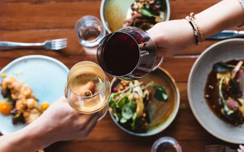 Wine glasses toasting over gourmet dishes at City Winery pairing experience.