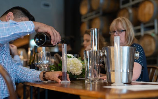 Wine blending workshop at City Winery with participants pouring wine into a measuring cylinder.