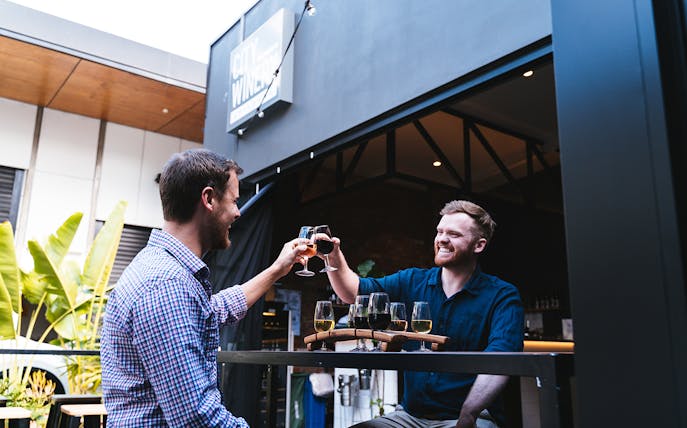 Men toasting wine glasses at City Winery during tasting experience.