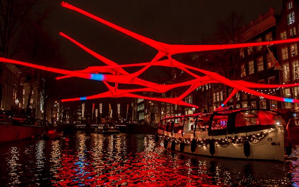 Amsterdam canal cruise with illuminated red art installation during Light Festival.