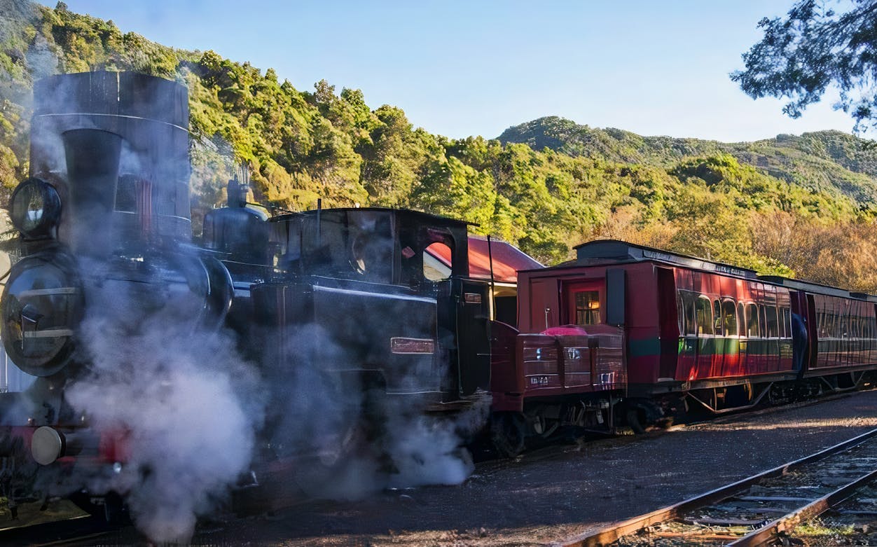 Steam train at King River Gorge with scenic mountain backdrop.