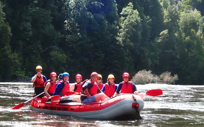 Group rafting adventure on a river surrounded by lush forest.