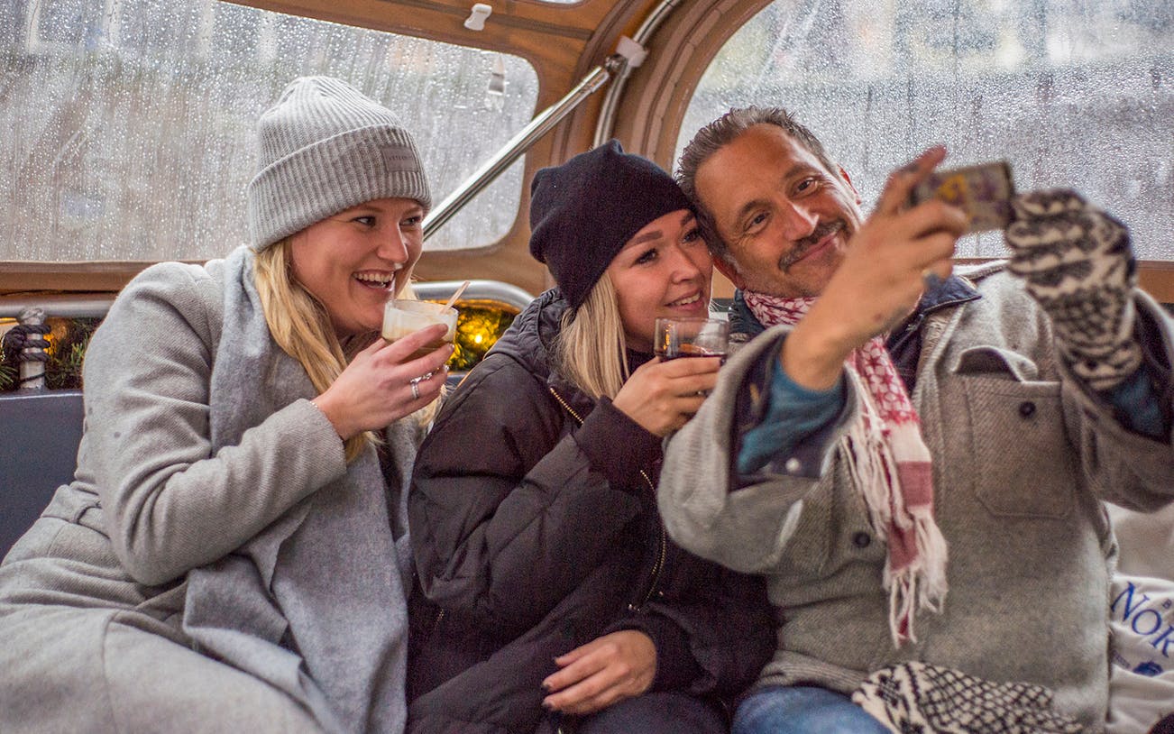 Guests enjoying drinks on a luxury canal cruise during the Amsterdam Light Festival.