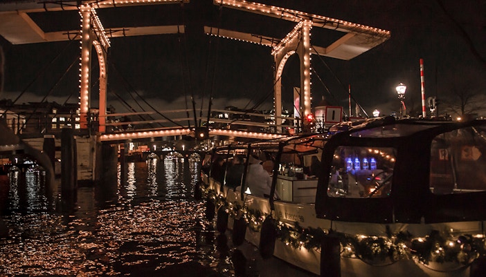 Amsterdam Light Festival canal cruise under illuminated bridge.