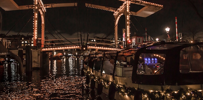 Amsterdam Light Festival canal cruise under illuminated bridge.