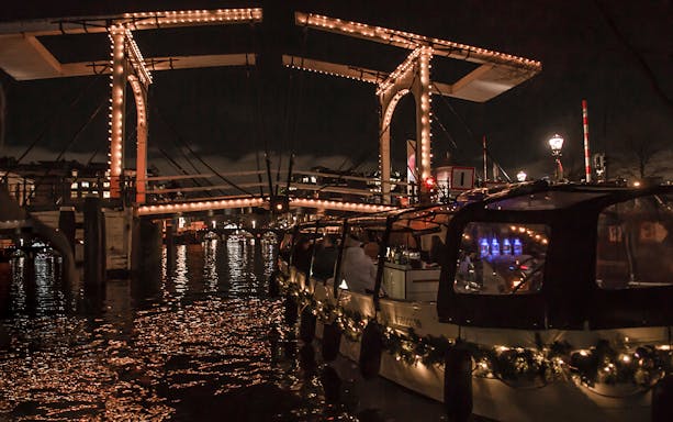 Amsterdam Light Festival canal cruise under illuminated bridge.