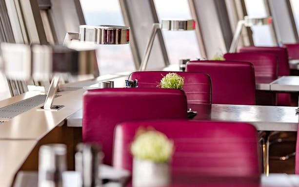 Dining area inside Berlin TV Tower with red chairs and tables.