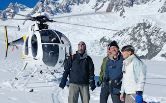 Helicopter tour group on snow at Fox Glacier with Mount Cook in background.