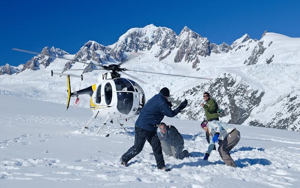 Helicopter flying over Fox Glacier with Mount Cook in the background, New Zealand.