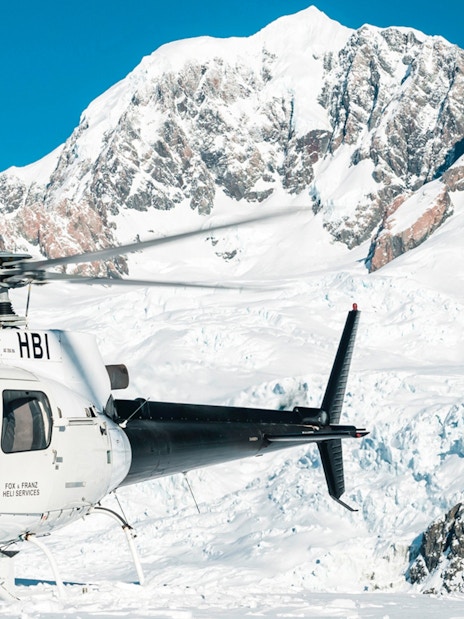 Helicopter on snow with Fox and Franz Josef Glaciers in background.