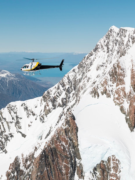 Helicopter flying over snow-covered Fox and Franz Josef Glaciers in New Zealand.