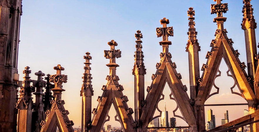 Milan Duomo rooftop spires with city skyline in the background.