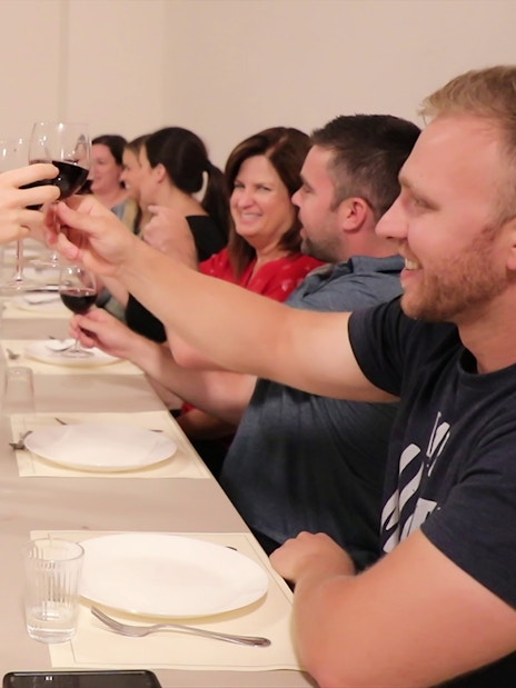 Small group toasting with wine during a cooking class dinner in Florence.