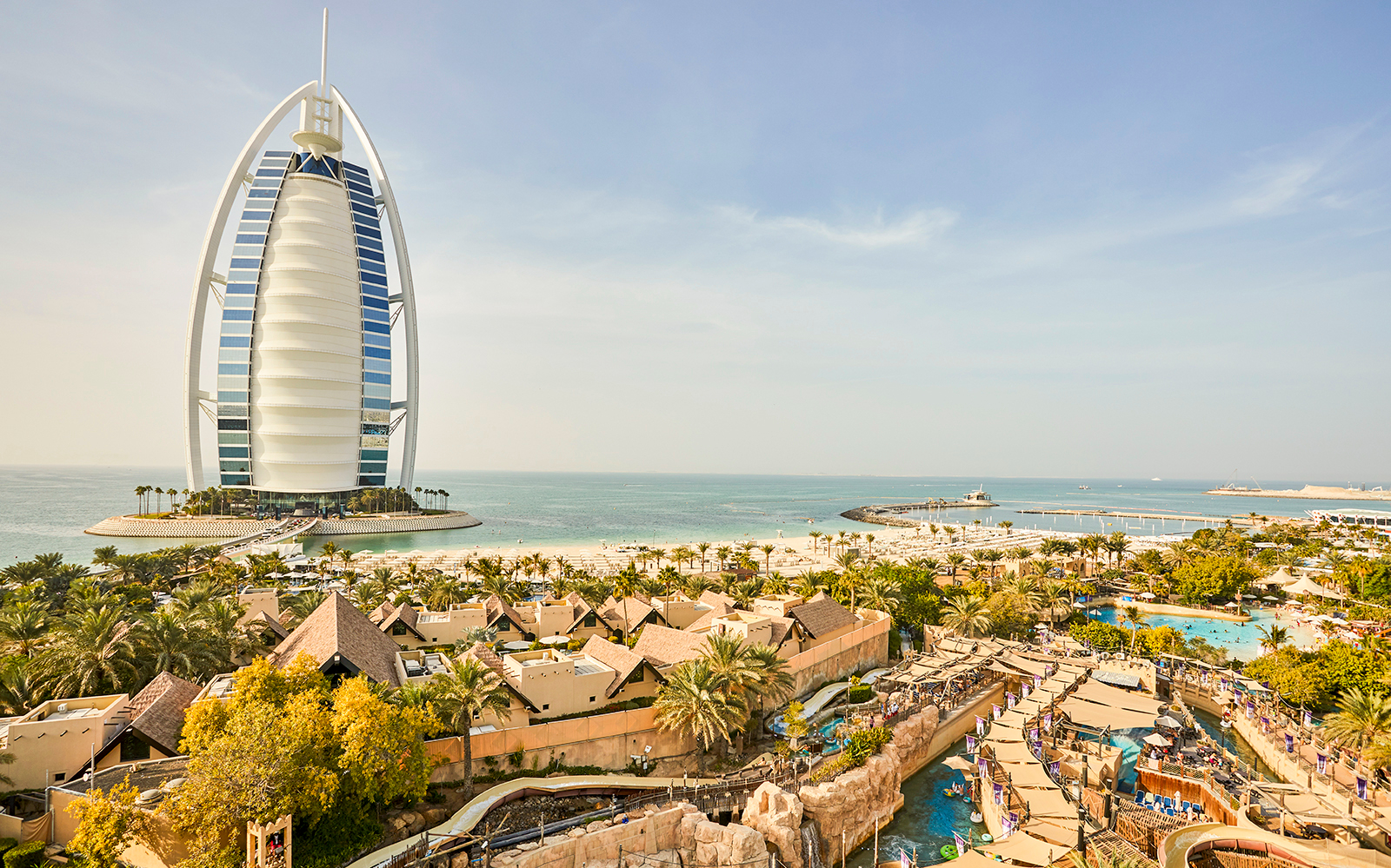 Wild Wadi Water Park with Burj Al Arab in Dubai, view of water slides and beach.