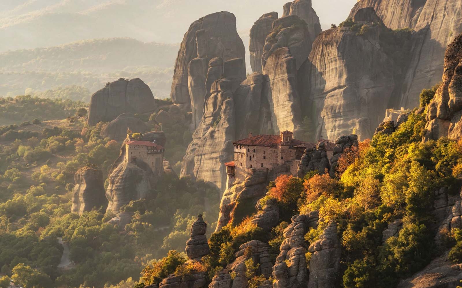 Meteora monasteries perched on rock formations at sunset, Greece.