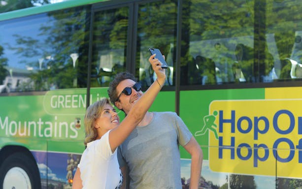 Tourists taking a selfie in front of a Hop On Hop Off bus in Salzburg.