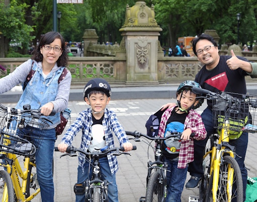 Family with bikes in Central Park, New York City, ready for a bike rental tour.