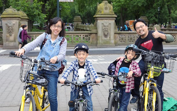 Family with bikes in Central Park, New York City, ready for a bike rental tour.