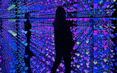 Visitor exploring Moco Museum Barcelona exhibit with colorful reflections and mirrors.