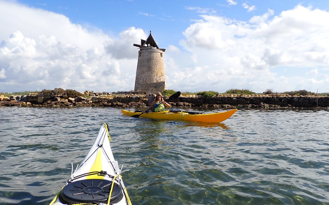 Kayaker near windmill in Stagnone Nature Reserve, Sicily.