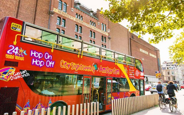 Red double-decker bus for Amsterdam city sightseeing tour near Heineken Brewery.