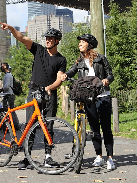 Couple with bikes near Brooklyn Bridge, New York City, enjoying a guided tour.