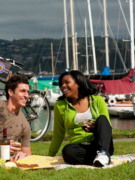 Couple enjoying a picnic by the bay with bikes on the Golden Gate Bridge to Sausalito tour.