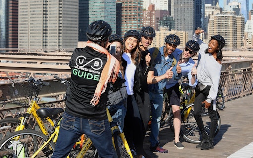 Group of cyclists with a guide on Brooklyn Bridge during a bike tour.