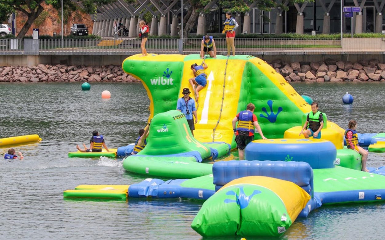 Participants enjoying inflatable obstacles at Darwin Waterfront Recreation Lagoon Aqua Park.