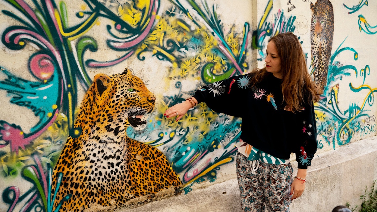 Street artist interacting with leopard mural on Belleville Street Art Tour.