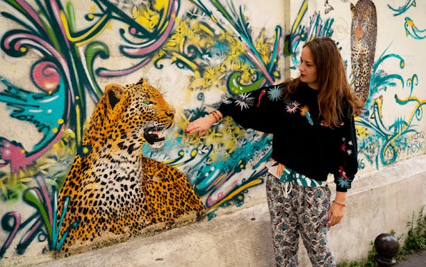 Street artist interacting with leopard mural on Belleville Street Art Tour.