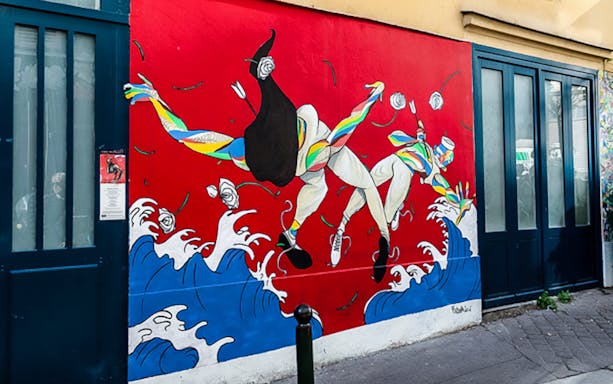 Colorful mural of dancers on a red wall in Montmartre, Paris.