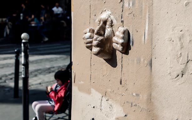 Montmartre street art sculpture on wall with blurred background.