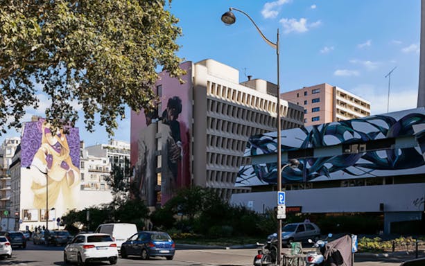 Street art murals on buildings in a city, featured in Murals XXL Street Art Tour.