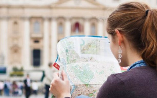 Woman studying a map in front of a historic building in Rome.