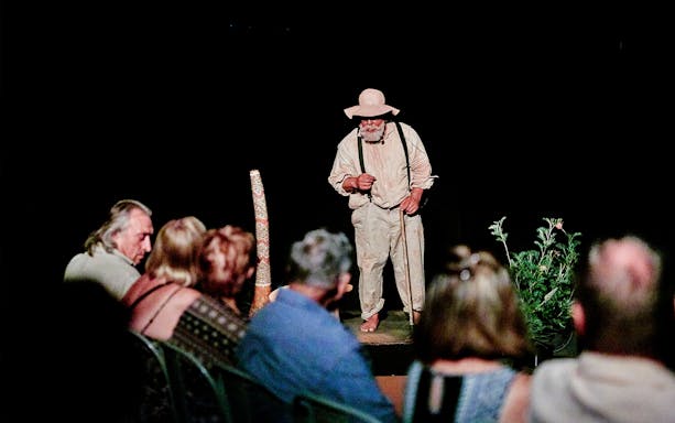 Performer on stage during Spirits of the Red Sand Evening Theatre Show with audience watching.